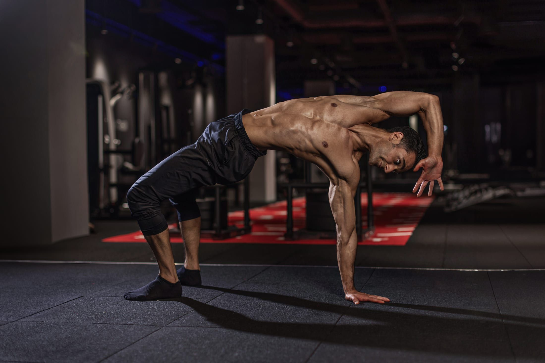 Gurinder Sandhu moving through a side-plank rotation drill on the gym floor at UNTIL Soho, London